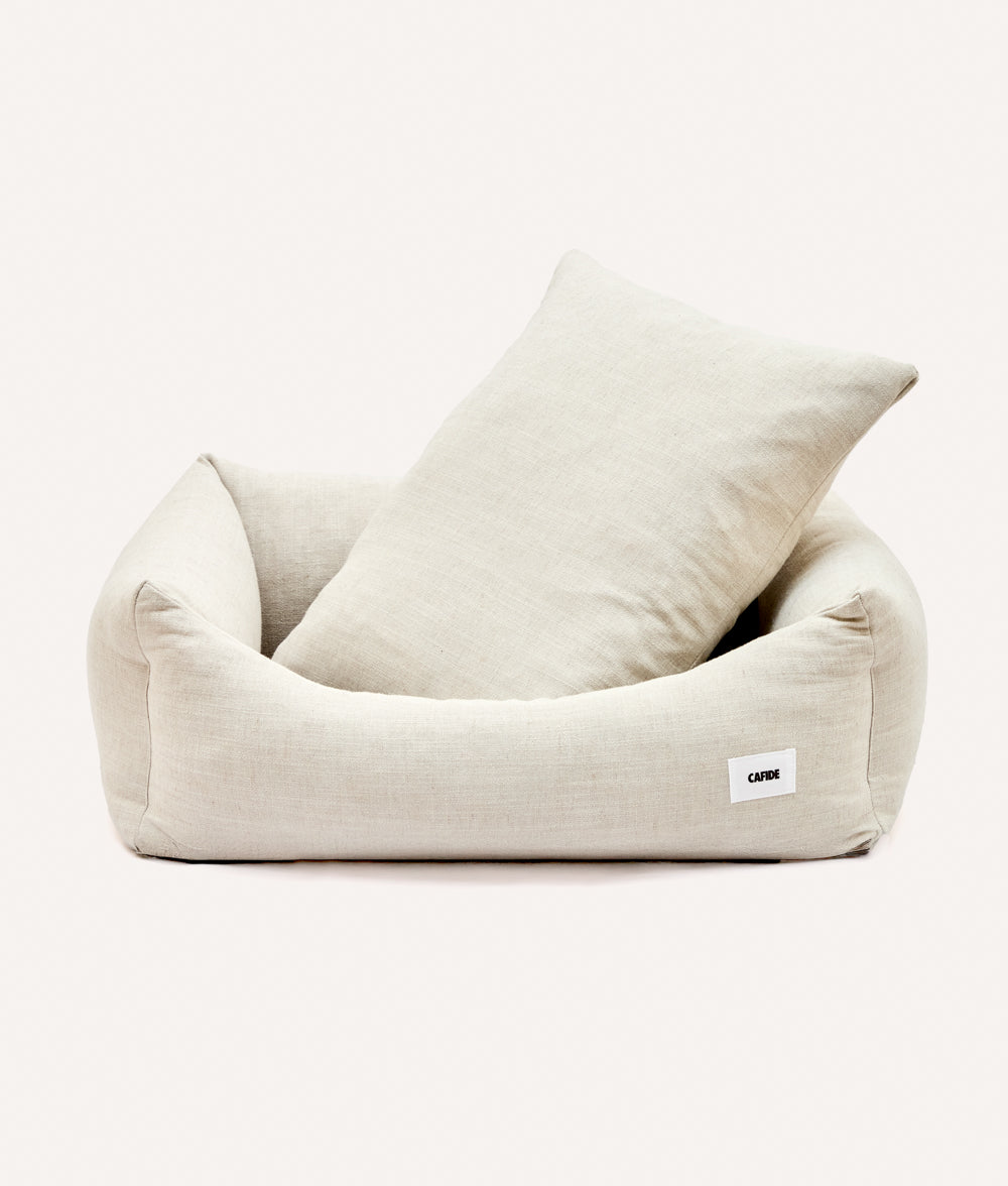 Cama para perro de tela tipo lino con cojín incluido sobre fondo neutro